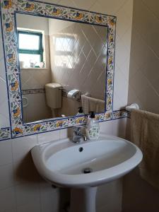 La salle de bains est pourvue d'un lavabo et d'un miroir. dans l'établissement Casa dos Avós, à São Brás de Alportel