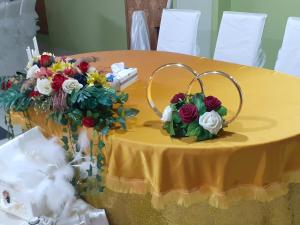 a yellow table with flowers and a ring on it at Hanul Anitei La paducel in Sărata-Nenciuleşti