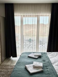 a bedroom with a bed with two towels and a large window at ICE-KOP Milmari in Kopaonik