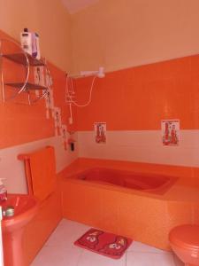 an orange bathroom with a toilet and a tub at Amalfi's Place in Pimentel