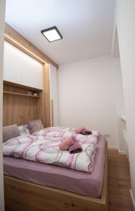 een slaapkamer met een bed met roze en witte lakens bij Cute 1BDR in City Center in Sarajevo