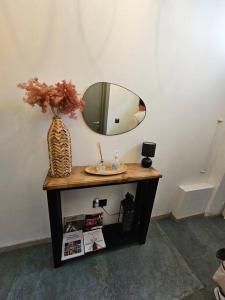 a table with a mirror and a vase on it at Dahlia apartment - Paola Modern Townhouse in Paola