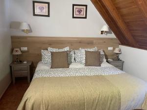 a bedroom with a large bed with two tables and two lamps at Hostal Escuils in Unha