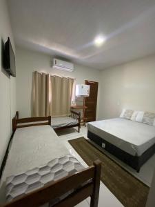 a bedroom with two beds and a television in it at POUSADA ORTEGA in Bodoquena