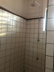 y baño con ducha de azulejos blancos. en Pied a Terre en Paramaribo