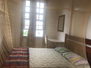 een bed in een kamer met een raam bij Pied a Terre in Paramaribo