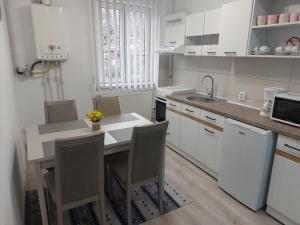 a kitchen with white cabinets and a table with chairs at La Radu in Lupeni