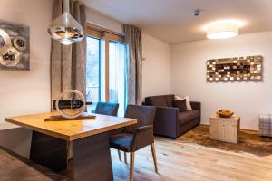 Spa Apartments - Zell am See في زيل أم سي: غرفة معيشة مع طاولة وكراسي وأريكة