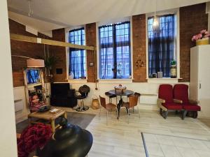 een woonkamer met een tafel, stoelen en ramen bij Characteristic loft style apartment in Birmingham