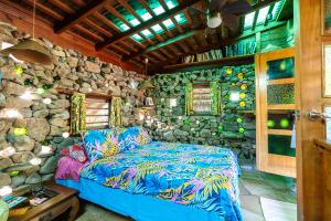 a living room with a couch and a stone wall at Heimanarii,slodge fetia in Haapiti