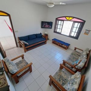 Una sala de estar con un sofá azul y sillas. en CASA DE PRAIA MARAVILHOSA PERUIBE, en Peruíbe