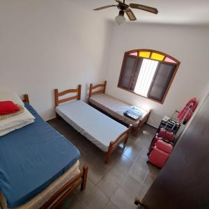 1 dormitorio con 2 camas, ventana y maleta en CASA DE PRAIA MARAVILHOSA PERUIBE en Peruíbe