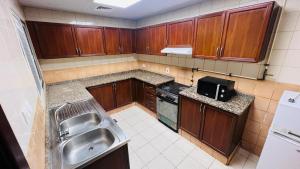 a small kitchen with wooden cabinets and a sink at Beautiful Bedroom in Al Barsha Near Mashreq Metro in Dubai