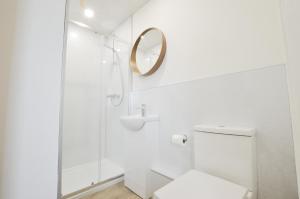 La salle de bains blanche est pourvue d'une douche et d'un miroir. dans l'établissement Viewpoint West, à Dunollie