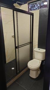 a bathroom with a toilet and a glass shower door at Hospedaje Villa Salome in Pereira