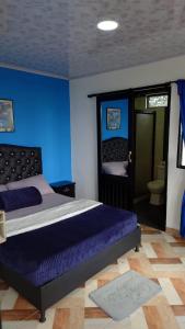 a bedroom with a bed with a blue wall at Hospedaje Villa Salome in Pereira