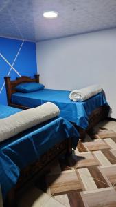 two beds in a room with blue walls at Hospedaje Villa Salome in Pereira