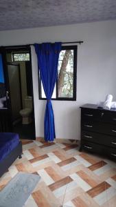 a bedroom with a blue curtain and a window at Hospedaje Villa Salome in Pereira