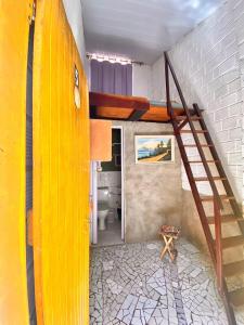 a room with a yellow staircase and a bathroom at Natus Hospedagem in Barra de São Miguel