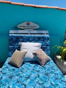 a blue wall with a bed with pillows on it at Caminho das Pedras Búzios in Búzios