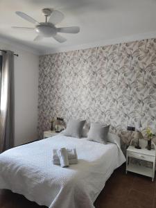 1 dormitorio con 1 cama blanca grande y pared en Relax, vistas, barbacoa y piscina, junto a Ronda en Arriate