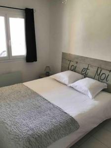 Una cama blanca con un letrero de no estar en casa. en Guest house « Cantegrit », en Ychoux