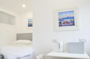 a white bedroom with a bed and a picture on the wall at Viewpoint East in Dunollie