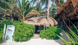 a resort with a straw umbrella and palm trees at Orchid House Tulum Beach in Tulum