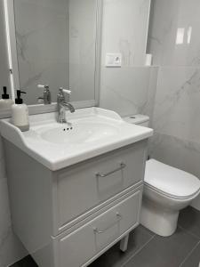 uma casa de banho branca com um lavatório e um WC em Maison Sereine em Valência