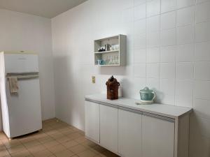 a kitchen with a white refrigerator and a counter at Apartamento no Centro para 7 pessoas in Campo Grande