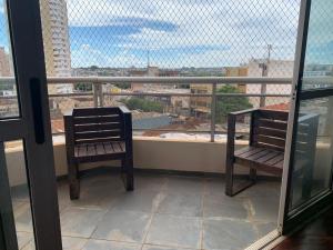 two chairs on a balcony with a view of a city at Apartamento no Centro para 7 pessoas in Campo Grande