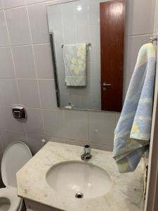 a bathroom with a sink and a toilet and a mirror at Apartamento no Centro para 7 pessoas in Campo Grande