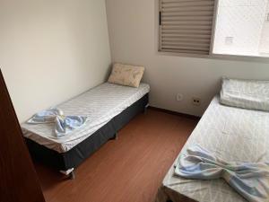 two twin beds in a room with a window at Apartamento no Centro para 7 pessoas in Campo Grande