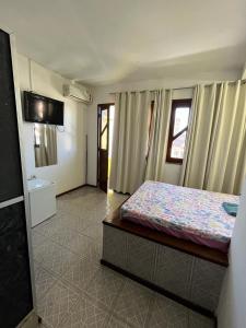 - une chambre avec un lit et une télévision murale dans l'établissement Pousada Realce, à Vera Cruz de Itaparica