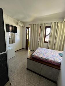 a bedroom with a bed and a tv on the wall at Pousada Realce in Vera Cruz de Itaparica