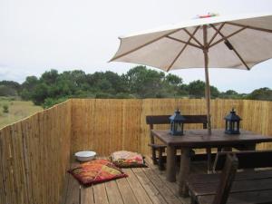 eine Holzterrasse mit einem Tisch und einem Sonnenschirm in der Unterkunft Rico Pino eco posada in La Pedrera