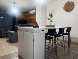 eine Küche mit einer Bar mit Hockern und einer Uhr in der Unterkunft Appartement à 2 mins du centre in Sarlat-la-Canéda