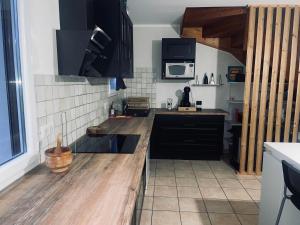 eine Küche mit schwarzen Schränken und einer hölzernen Arbeitsplatte in der Unterkunft Appartement à 2 mins du centre in Sarlat-la-Canéda