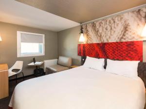 a bedroom with a large bed with a red headboard at ibis Bordeaux Centre Meriadeck in Bordeaux