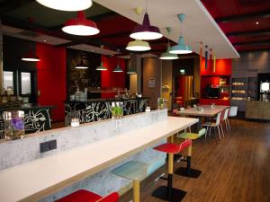 a restaurant with a counter and tables and chairs at ibis Köln Messe in Cologne
