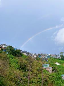 een regenboog over een heuvel met huizen en bomen bij Belle House Đà Lạt in Da Lat