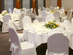 una habitación con mesas y sillas blancas con mesas y flores blancas en ibis Styles Luzern, en Lucerna