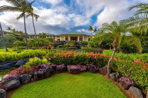 a garden with flowers and palm trees in front of a house at Grand Hyatt Kauai Resort & Spa in Koloa