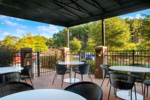eine Terrasse mit Tischen, Stühlen und einem Zaun in der Unterkunft Hyatt Place Raleigh Cary in Raleigh