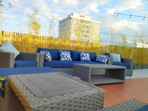 a patio with a blue couch and tables and a fence at Hotel NEXT in Guadalajara