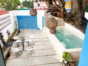 a patio with a pool and chairs and a tree at CASA MINERVA MERIDA in Mérida