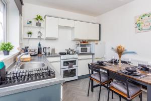 a kitchen with white cabinets and a sink and a table at New Large 2 Bed entire apartment Near Newcastle upon Tyne with Free Parking in Kenton