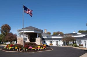 a flag flying in front of a building with flowers at Cherry Valley Hotel, BW Premier Collection in Newark