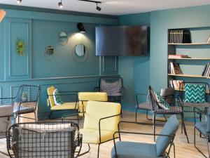 uma sala de espera com cadeiras e uma televisão de ecrã plano em ibis Styles Lille Neuville en Ferrain em Neuville-en-Ferrain