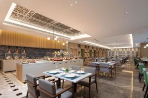 a restaurant with tables and chairs and a kitchen at Hilton Garden Inn Shenzhen Guangming Hongqiao Park in Shenzhen